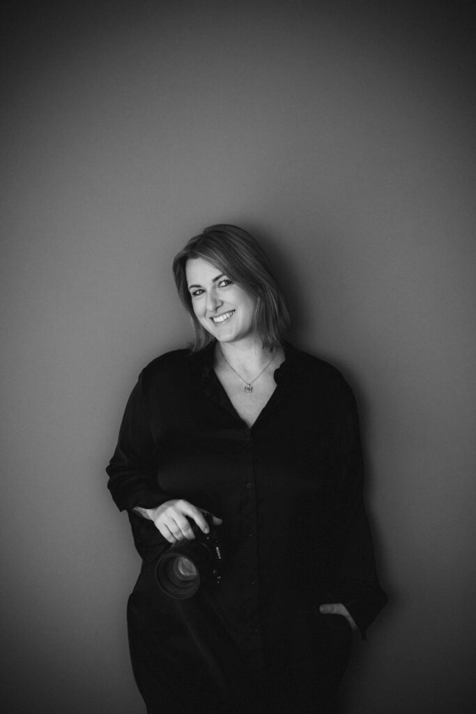 Fotografin steht mit Kamera in der Hand in ihrem Studio in Bruchsal und lächelt nett